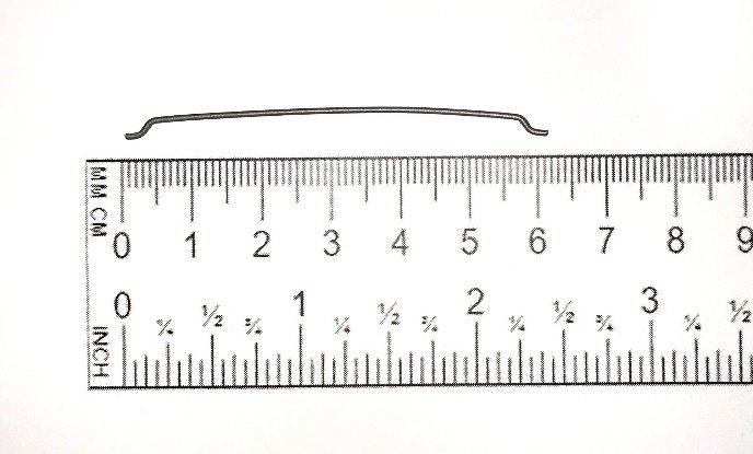 A hooked-end steel fiber about 60 mm long beside a ruler