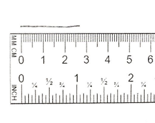 A twisted steel fiber about 25 mm long beside a ruler
